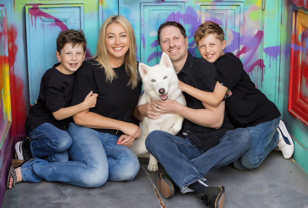 Family portrait session in downtown Santa Ana with grafitti in the background and their white husky including in the portrait.