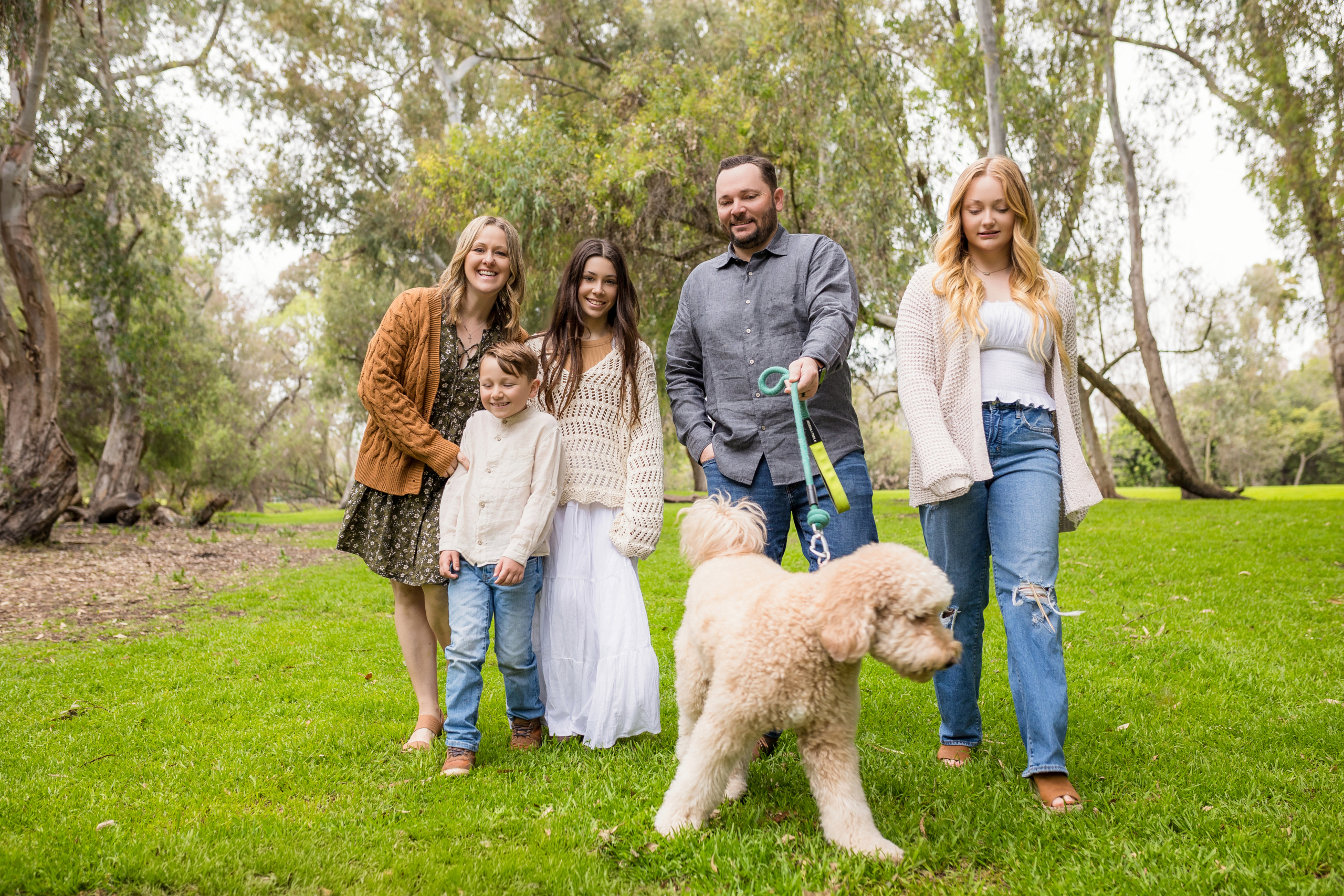 Candid Family photography at Huntington Beach Central park wearing fall colors and walking their labradoodle dog.