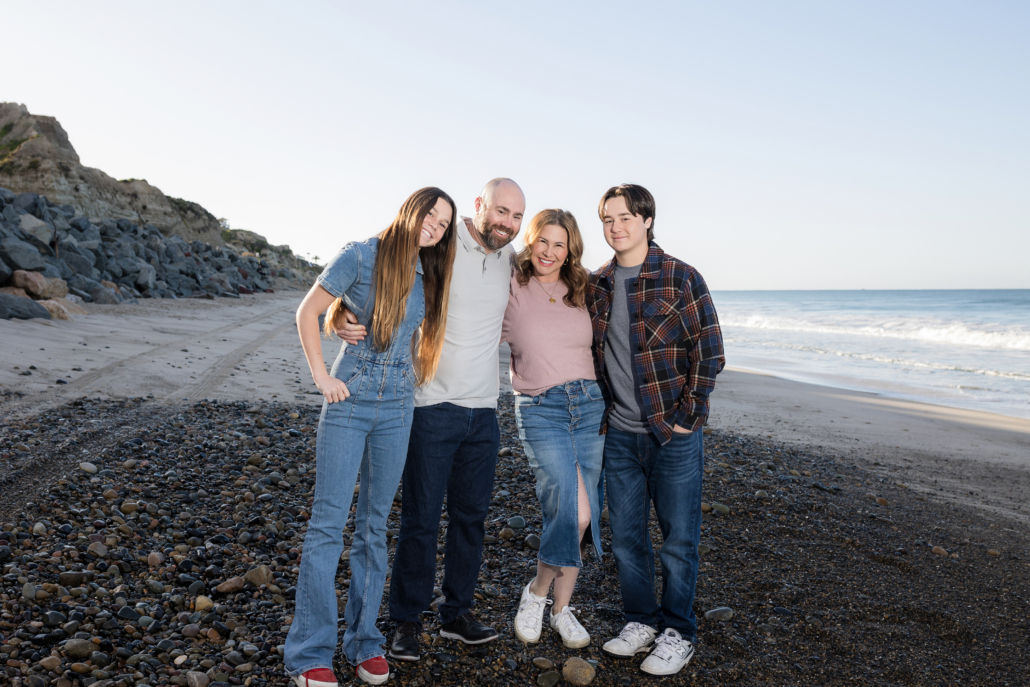 Family of four posing with the ocean in the background at San Clemente State Beach