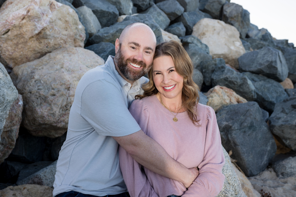 Intimate portrait of mom and dad sitting on a rock at San Clemente Beach, captured by a professional photographer.