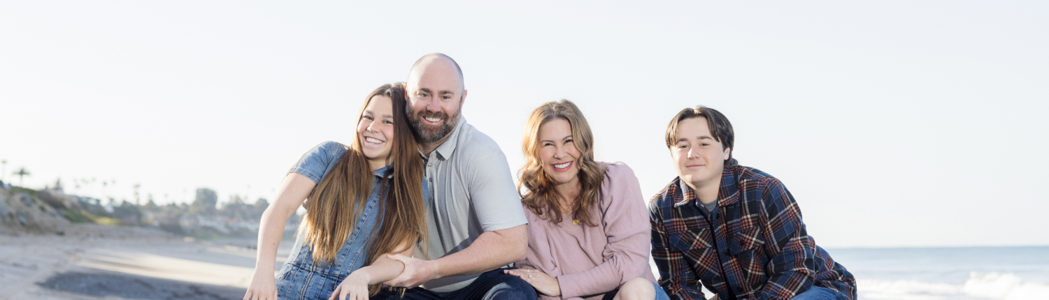 Family of four enjoying their photoshoot on the sandy shores of San Clemente Beach.