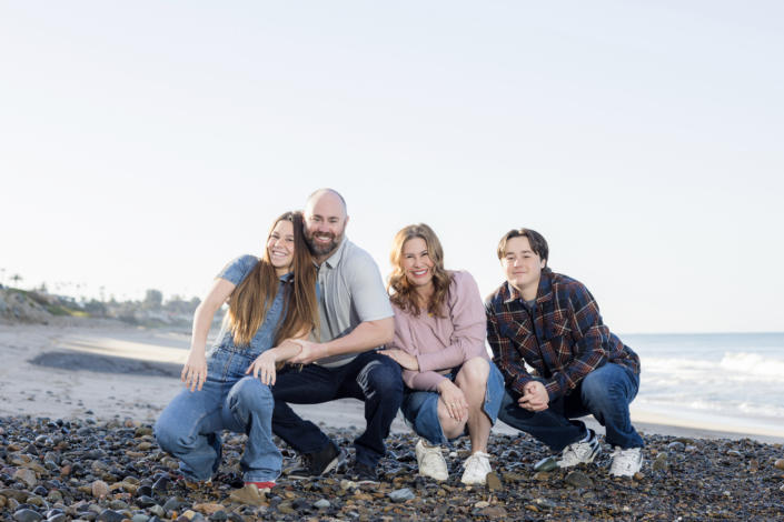 Family of four enjoying their photoshoot on the sandy shores of San Clemente Beach.