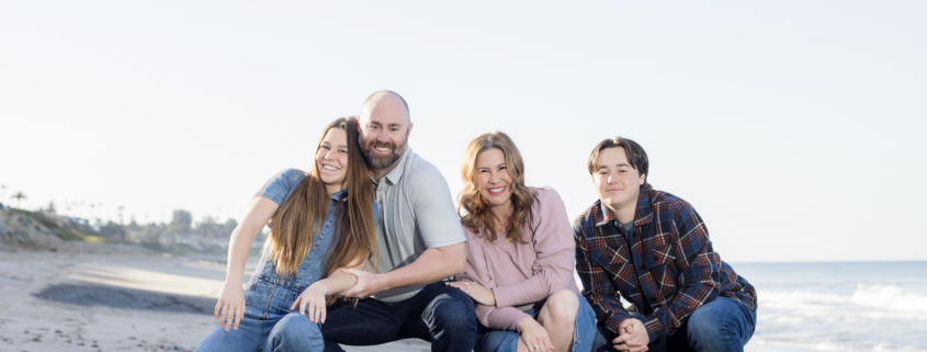 Family of four enjoying their photoshoot on the sandy shores of San Clemente Beach.