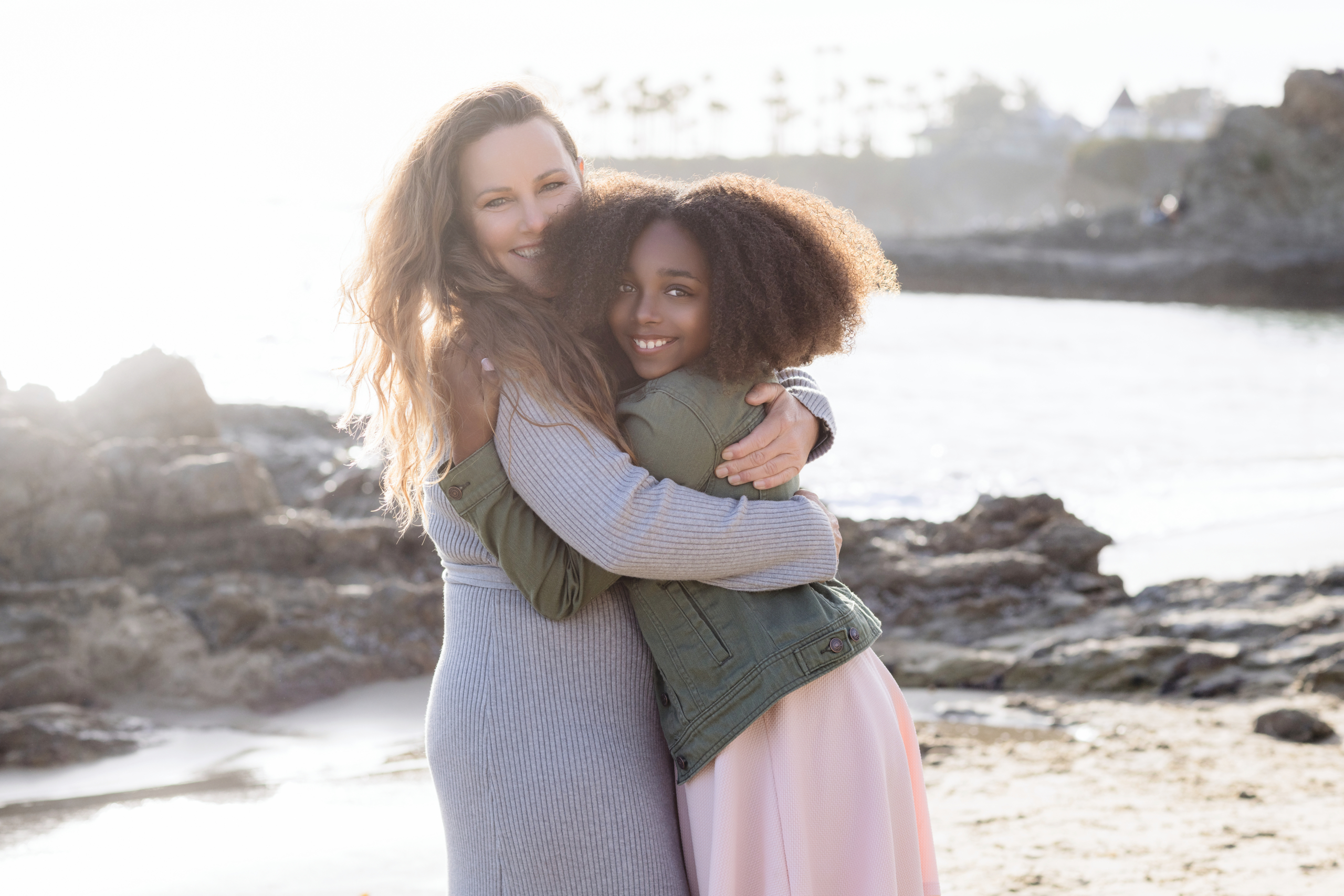 Single mom and daughter sharing a joyful moment on the sandy shore of Laguna Beach.