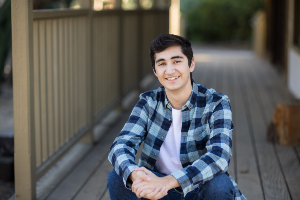 "Senior boy photo session in an urban setting with rustic wood textures and a rustic building in Orange County, showcasing a stylish and modern look."